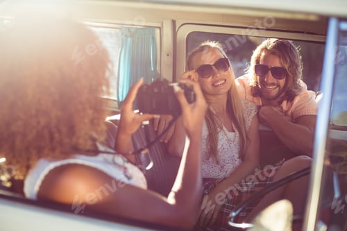 Preview: Woman taking photograph of friends in campervan