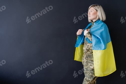 Preview: side view of military woman with ukrainian flag on shoulders looking away isolated on black