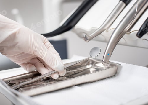 Preview: Dentist with gloved hand is picking dental tool in dental office