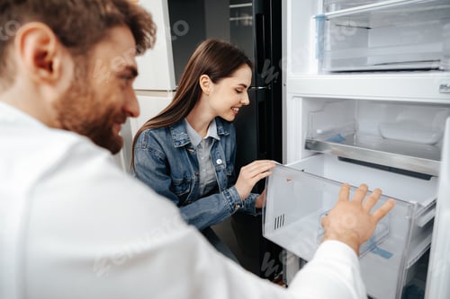 Preview: Young couple selecting new refrigerator in household appliance store
