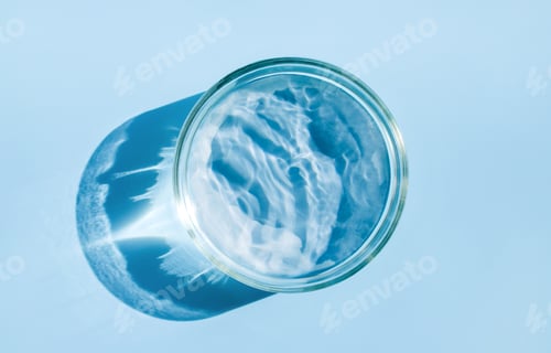 Preview: petri dish with liquid water on plain blue background water ripple texture
