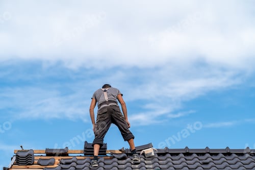 Preview: workman on the roof of a family house, building a roof covering from ceramic tiles