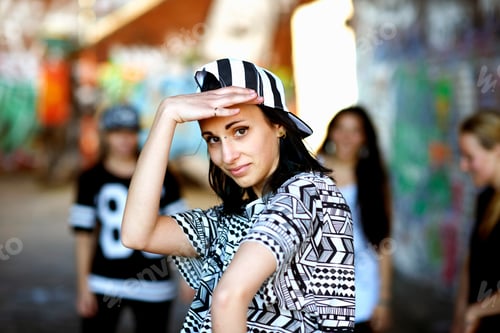 Preview: Young woman wearing baseball cap backwards, looking at camera