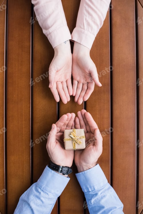 Preview: cropped image of boyfriend gifting present box to girlfriend
