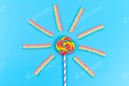 Preview: a top view colored lollipop along with chewing marmalades on the blue background rainbow sugar sweet