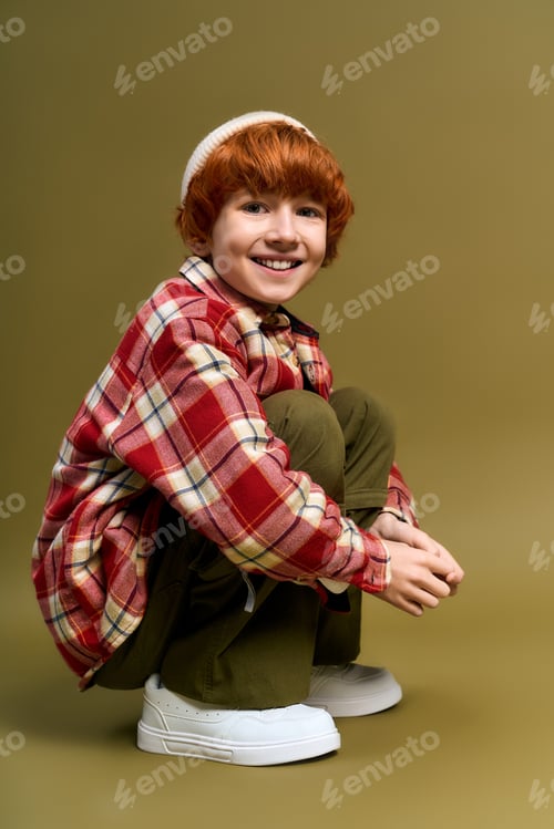 Preview: Little stylish boy showcases trendy fashion in a cozy indoor setting