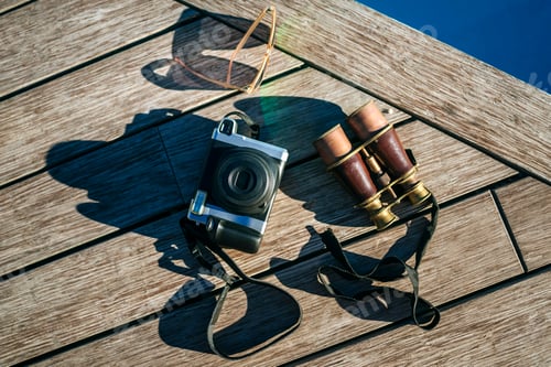 Preview: Camera, vintage binoculars and sunglasses on wooden deck