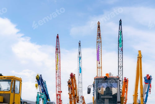 Preview: Close-up mobile crane, yellow bulldozer, and blue backhoe parked at second-hand machinery auction