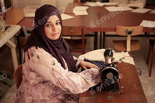 Preview: A seamstress of Arab origin sews a garment on her sewing machine.