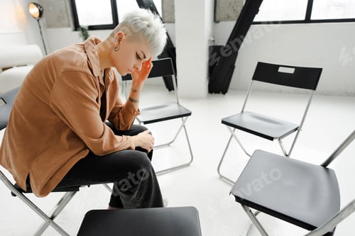 Preview: Sad, unhappy young woman with piercing and tattoo sitting on chair having stress or depression