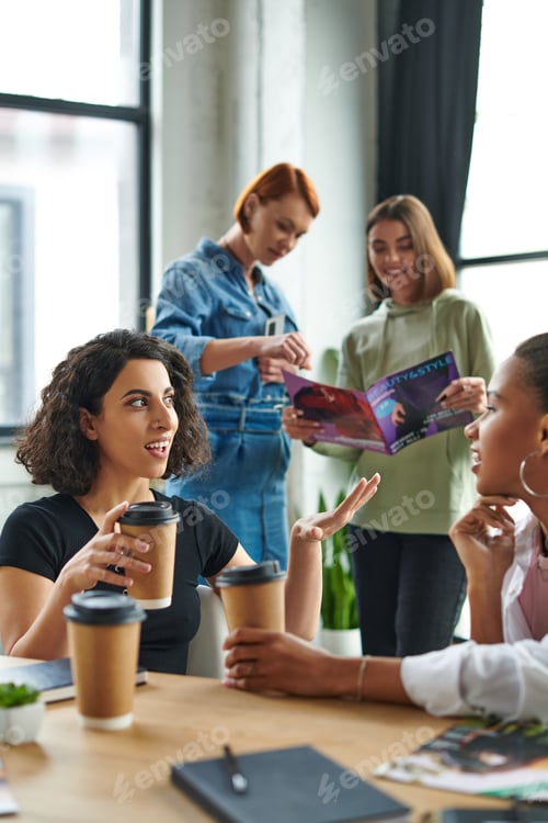 Preview: multiracial woman with takeaway drink gesturing and talking to african american girlfriend