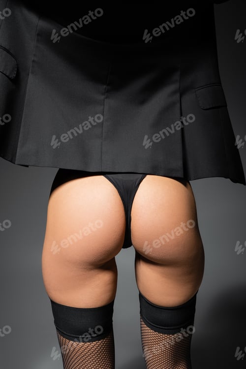Preview: partial view of seductive female model with sexy buttocks posing in panties and black blazer on grey