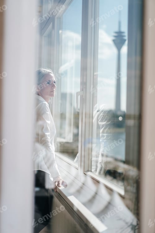 Preview: Businesswoman looking out of window