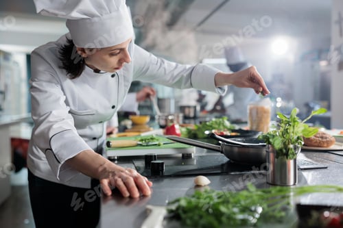 Preview: Culinary expert putting fresh chopped herbs in pan while cooking gourmet dish