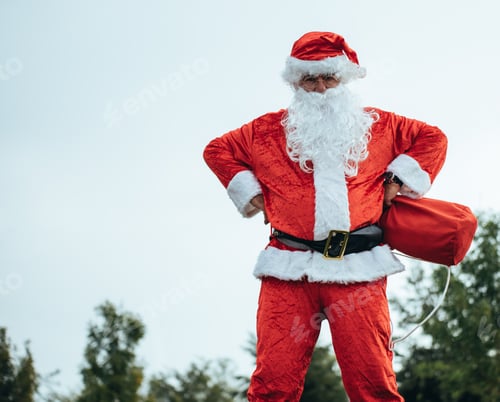 Preview: Santa Claus standing with arms resting on his hips grabbing his red bag