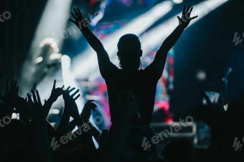 Preview: Silhouette of a woman with raised hands on a concert