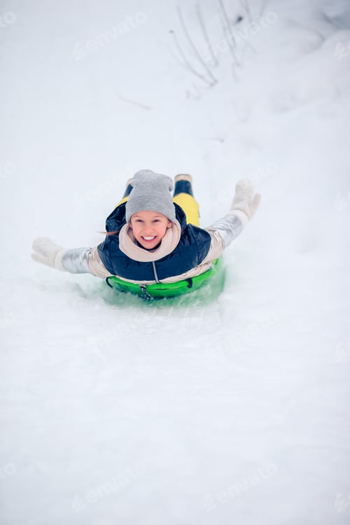 Preview: Adorable little happy girl sledding in winter snowy day