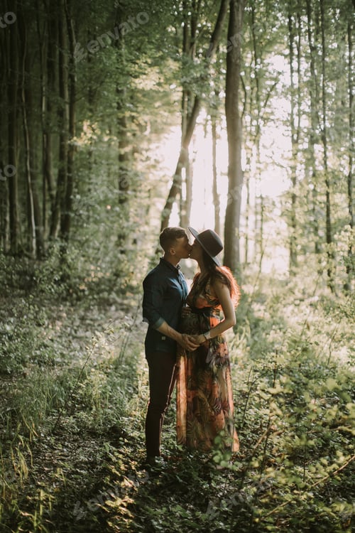 Preview: Happy pregnant woman and her man, kissing and hugging each other, walking in the forest