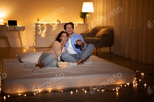 Preview: Cheerful Millennial Couple Watching Television And Eating Popcorn At Home