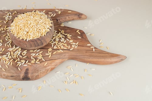 Preview: Yellow rice seeds in a wooden cup on concrete background