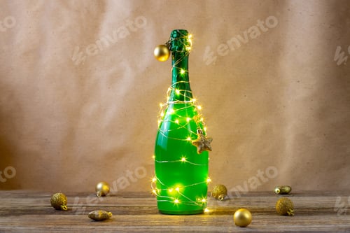 Preview: a bottle of green champagne wrapped in a glowing garland like a Christmas tree. New year concept