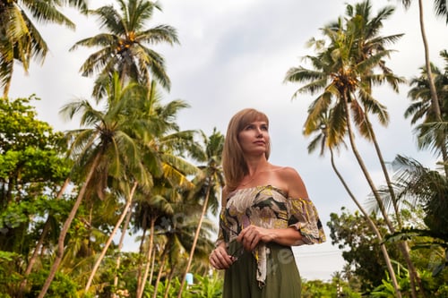 Preview: Middle aged lady at tropical jungles background, looking away. Smiling adult woman