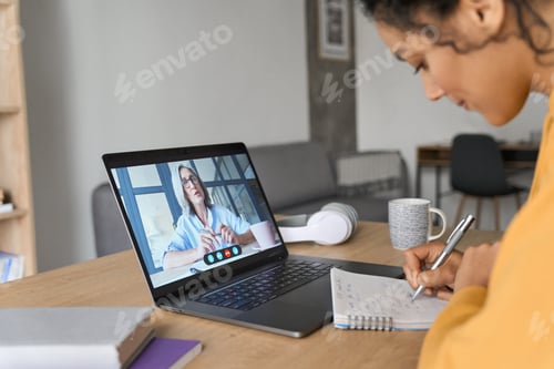 Preview: Woman Teleconferencing with Colleague and Taking Notes