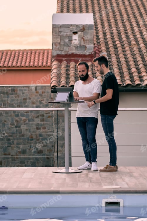 Visualização: Dois jovens empresários conversando sobre negócios enquanto trabalhavam on-line com seus tablets em