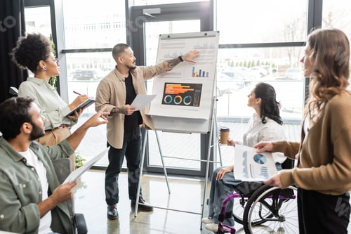 Preview: inclusion, asian man showing charts and graphs and planning work with team and woman in wheelchair