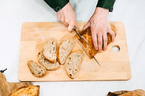Preview: Person Slicing Artisan Bread on Cutting Board. Artisan homemade bread free from additives and