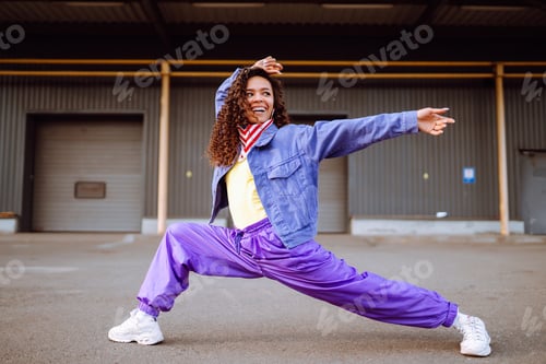 Preview: Funky young woman with american bandana dancing alone in the street.Sport, dancing and urban culture