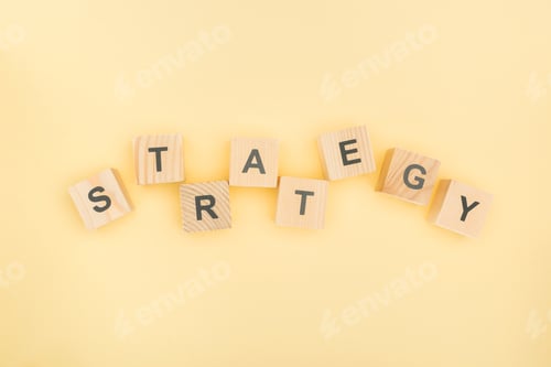 Preview: top view of strategy lettering made of wooden blocks on yellow background