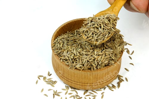 Preview: Chef taking chopped dry cumin seeds or zira spices from wooden spice jar.