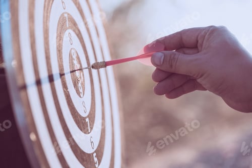 Preview: Close up hand throw red dart arrow hitting target centre dartboard