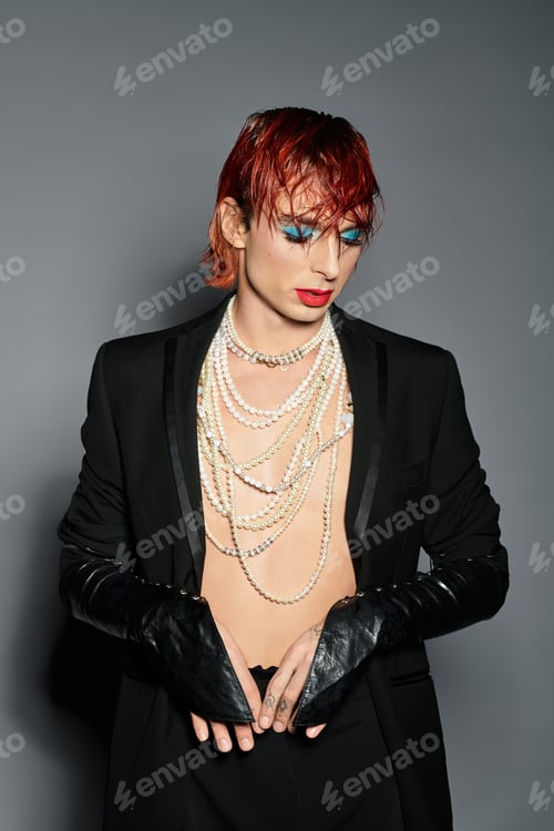 Preview: A young man showcases a striking look with bold makeup and stylish accessories, captured indoors.