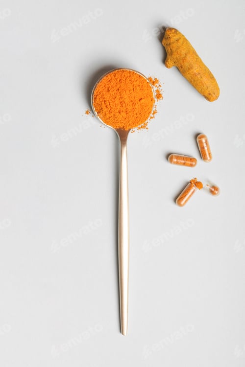 Preview: health care lifestyle concept. spoon with turmeric powder, root and pills on blue background.