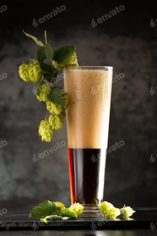 Preview: Glass of dark beer with hops around on a dark background