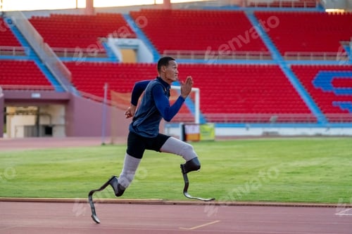 Preview: Asian para-athletes with prosthetic blades sprint on a running track at stadium.