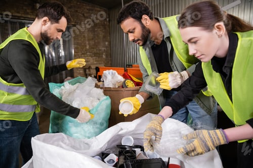 Preview: Indian sorter in high visibility vest and gloves holding plastic trash for recycling near sack