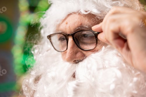 Preview: Close up of old man dressed as Christmas character struggling to read letters