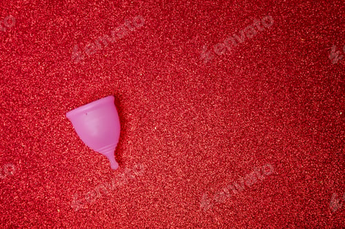 Preview: pink menstrual cup on shiny red background,top view. Zero waste concept.