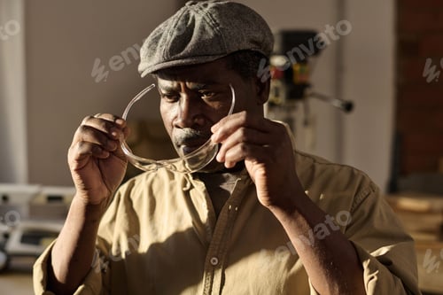 Preview: Black Senior Carpenter Putting on Protective Glasses in Workshop