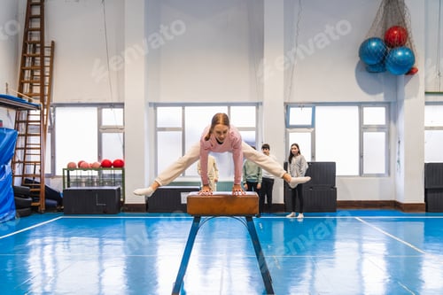 Preview: Girl practicing gymnastics on pommel horse in school gym with classmates watching