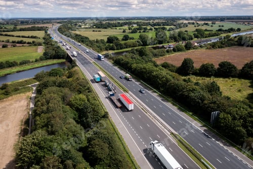 Preview: Aerial view directly above a busy UK motorway bridge over a river