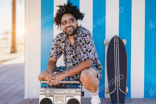 Preview: African american man listening music playlist - Skater boy with vintage boombox next to the beach