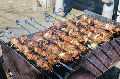 Preview: Meat on iron skewers, cooked on an open fire. Shish kebab roasted outdoors. Picnic.