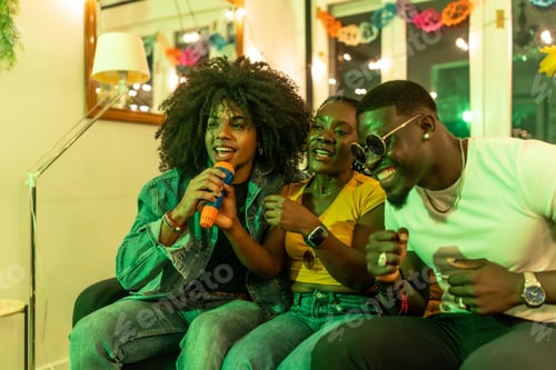 Preview: Man singing karaoke sitting on sofa with multi-ethnic friends