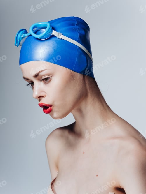 Preview: Portrait of a woman swimmer in a blue cap and glasses on the head bared shoulders
