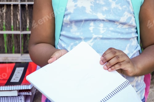 Preview: detail of unrecognizable school girl with backpack and books at school entrance.