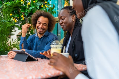 Preview: Diverse friends enjoying drinks and discussing on digital tablet
